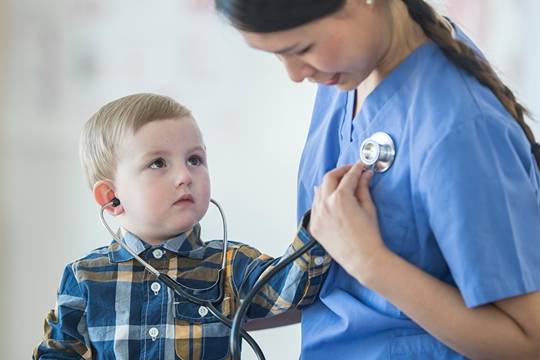 Young boy putting a stethiscope on the chest of a nurse