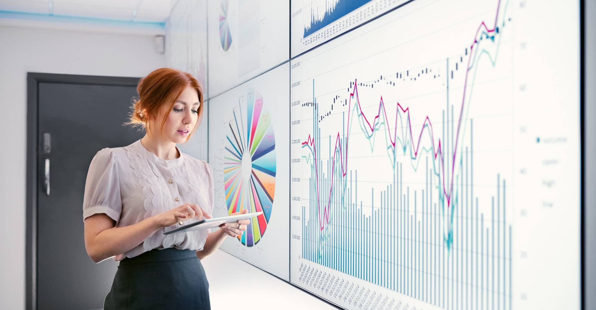 Un collaborateur examine des données et des graphiques sur un grand écran.