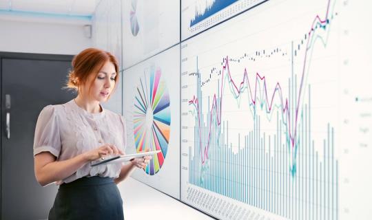 Un collaborateur examine des données et des graphiques sur un grand écran.