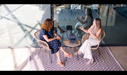 Two female colleagues having a meeting at a small table.