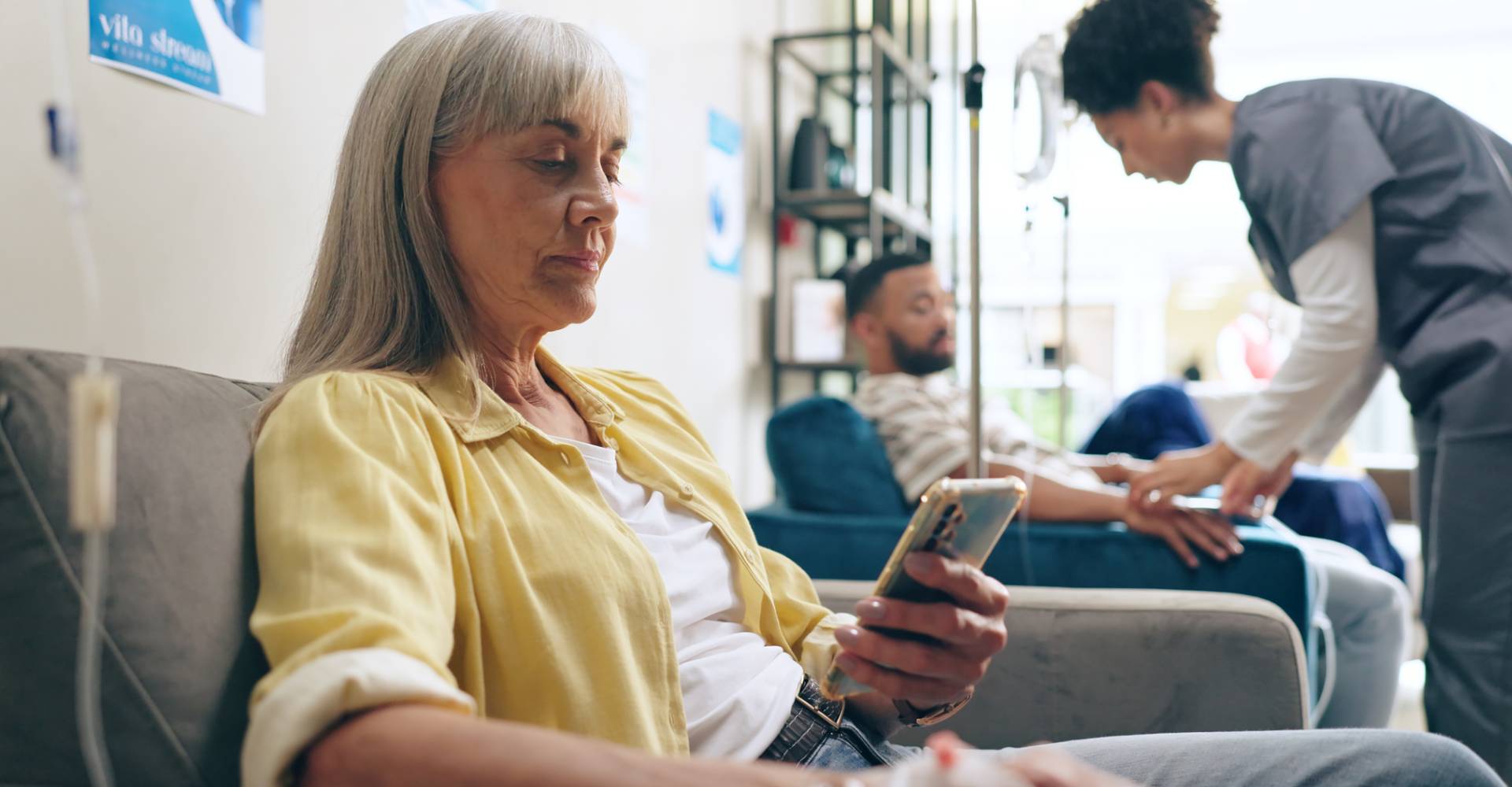 Female patient using a cellphone while receiving an infusion.