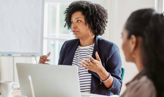 Group of women having a business meeting sitting at a table in an office.