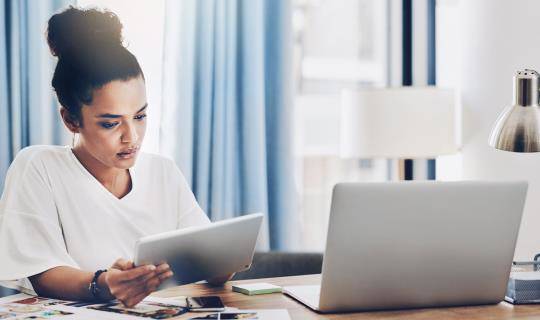 Shot of a young businesswoman using a digital tablet and laptop while working in her home office