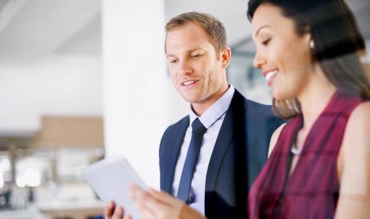 Deux collègues travaillant ensemble sur une tablette numérique dans un bureau