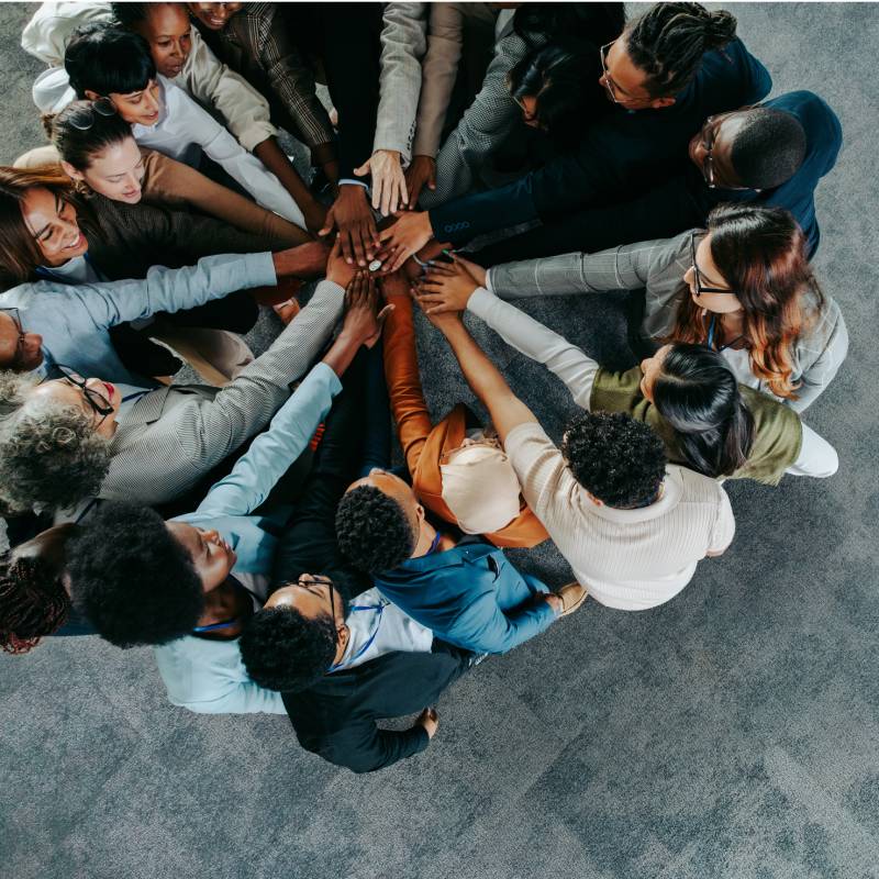 A group of teammates in a circle with their hands all gathered in the centre.