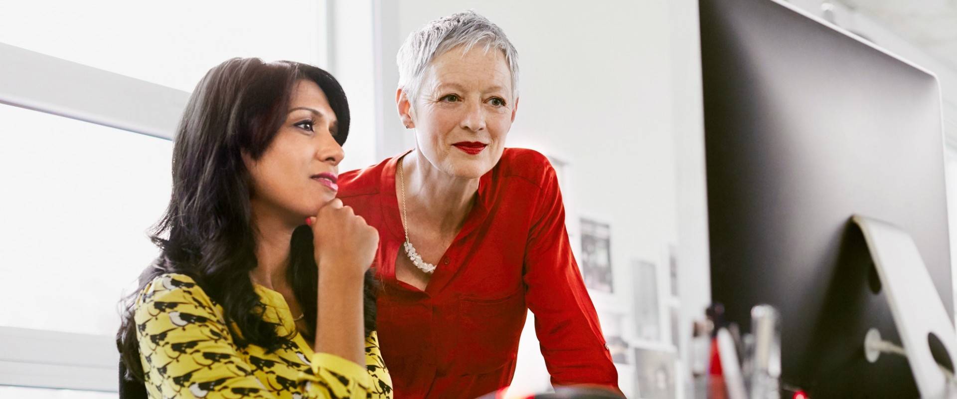Two female colleagues looking at a computer screen together.