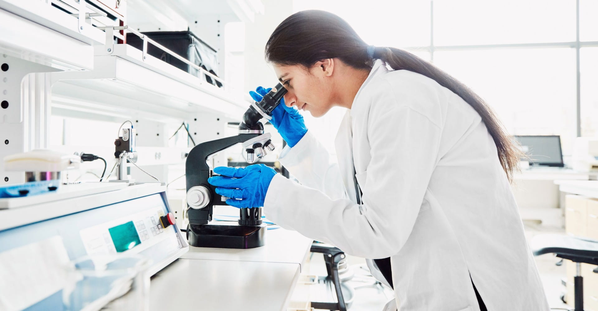 A scientist looking into a microscope.