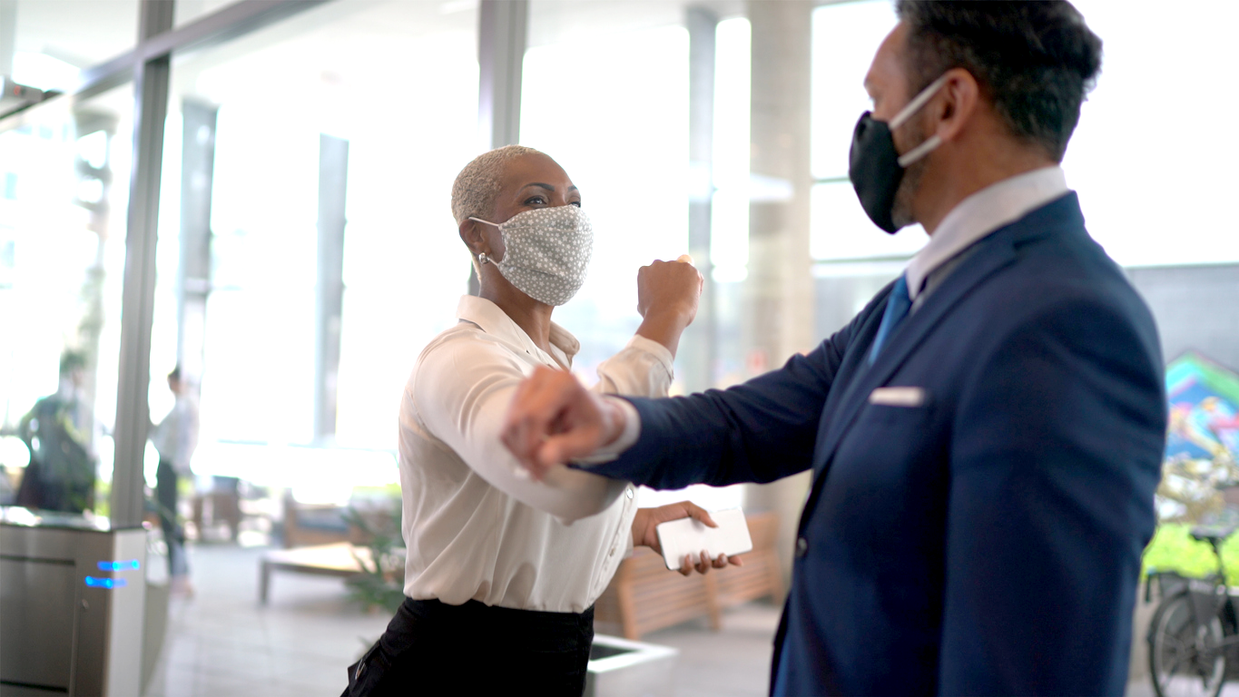 Two employees elbow shaking with masks on.